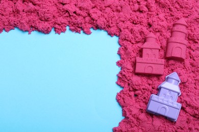 Pink kinetic sand and toy on light blue background, flat lay. Space for text