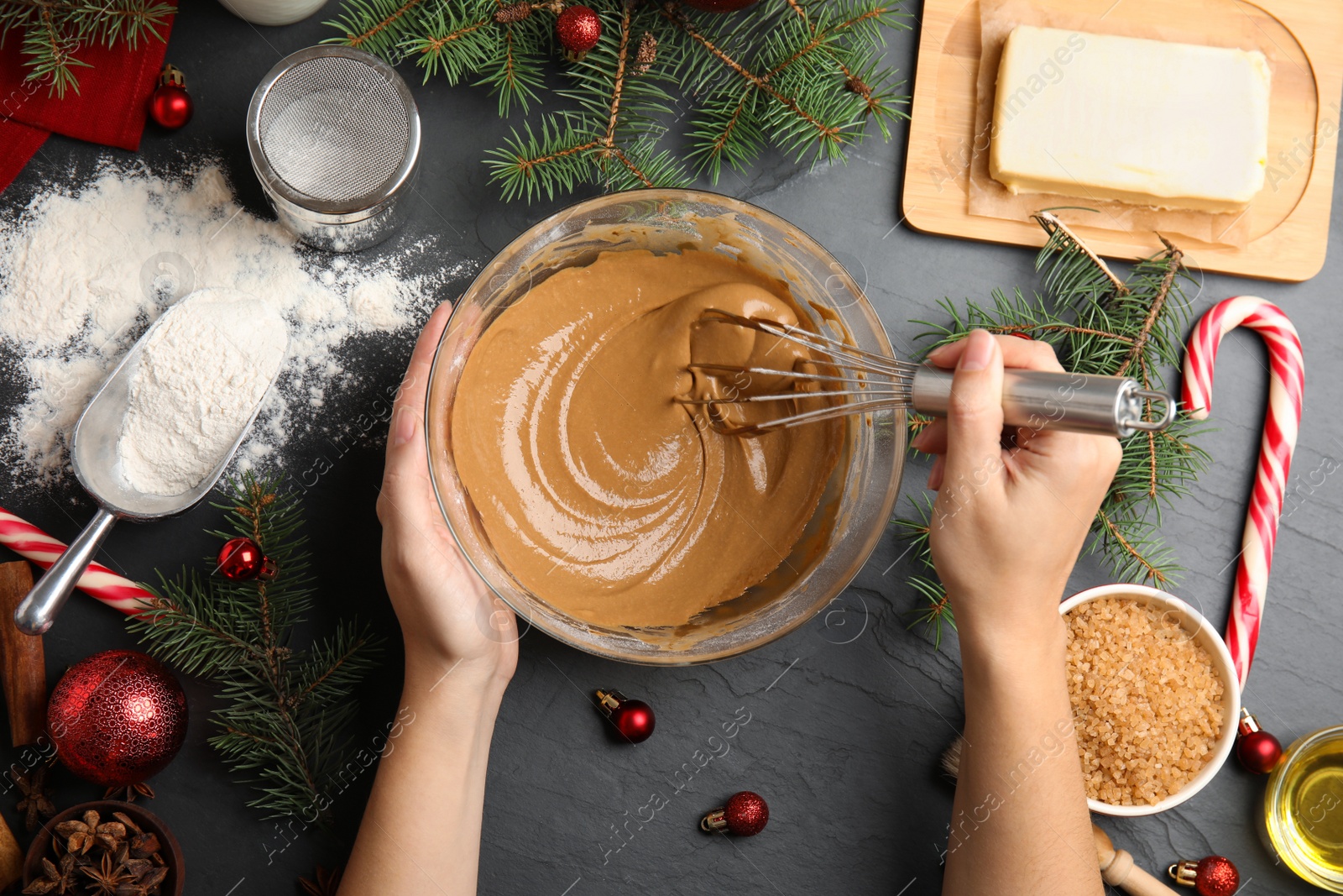 Photo of Woman cooking traditional Christmas cake at grey table with ingredients, top view