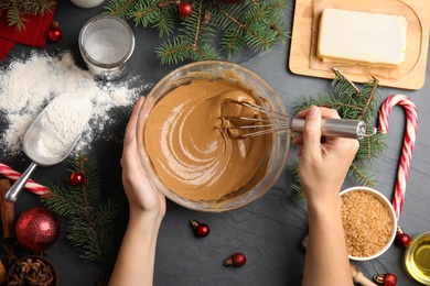 Woman cooking traditional Christmas cake at grey table with ingredients, top view
