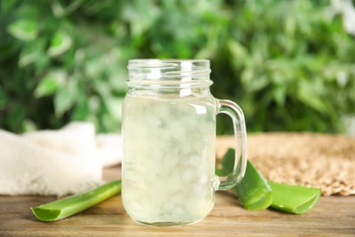 Photo of Fresh aloe drink in mason jar and leaves on wooden table