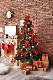 Photo of Beautiful Christmas tree and gifts near decorative fireplace with stockings indoors