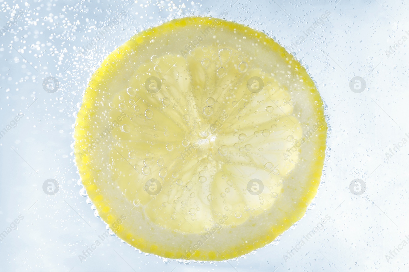 Photo of Juicy lemon slice in soda water, closeup