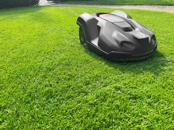 Modern robot lawn mower on green grass in garden