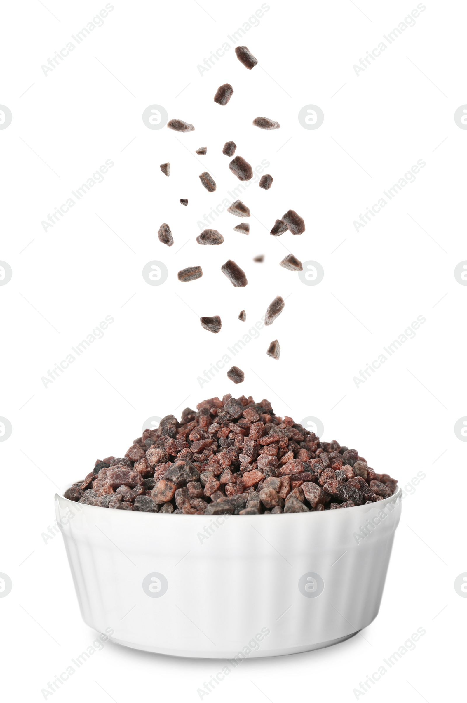 Image of Black salt crystals falling into bowl on white background