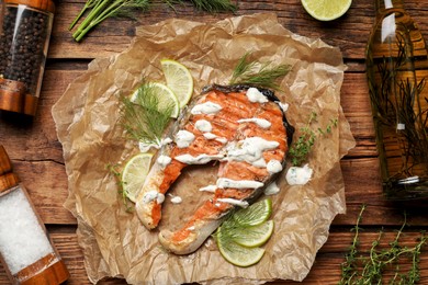 Photo of Tasty salmon steak with sauce, spices and oil on wooden table, flat lay