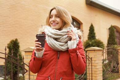 Young woman with cup of coffee walking outdoors