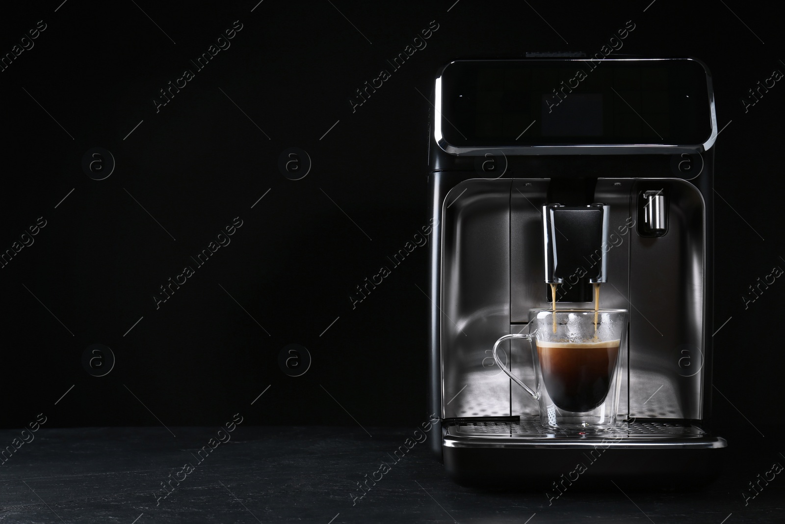 Photo of Making coffee with modern espresso machine on grey table against black background. Space for text