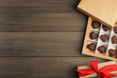 Tasty heart shaped chocolate candies on wooden table, flat lay with space for text. Happy Valentine's day