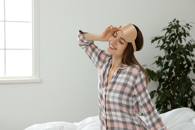 Photo of Beautiful woman wearing pajamas and sleep mask indoors. Bedtime