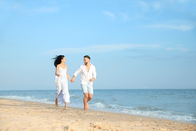 Happy young couple running together on beach