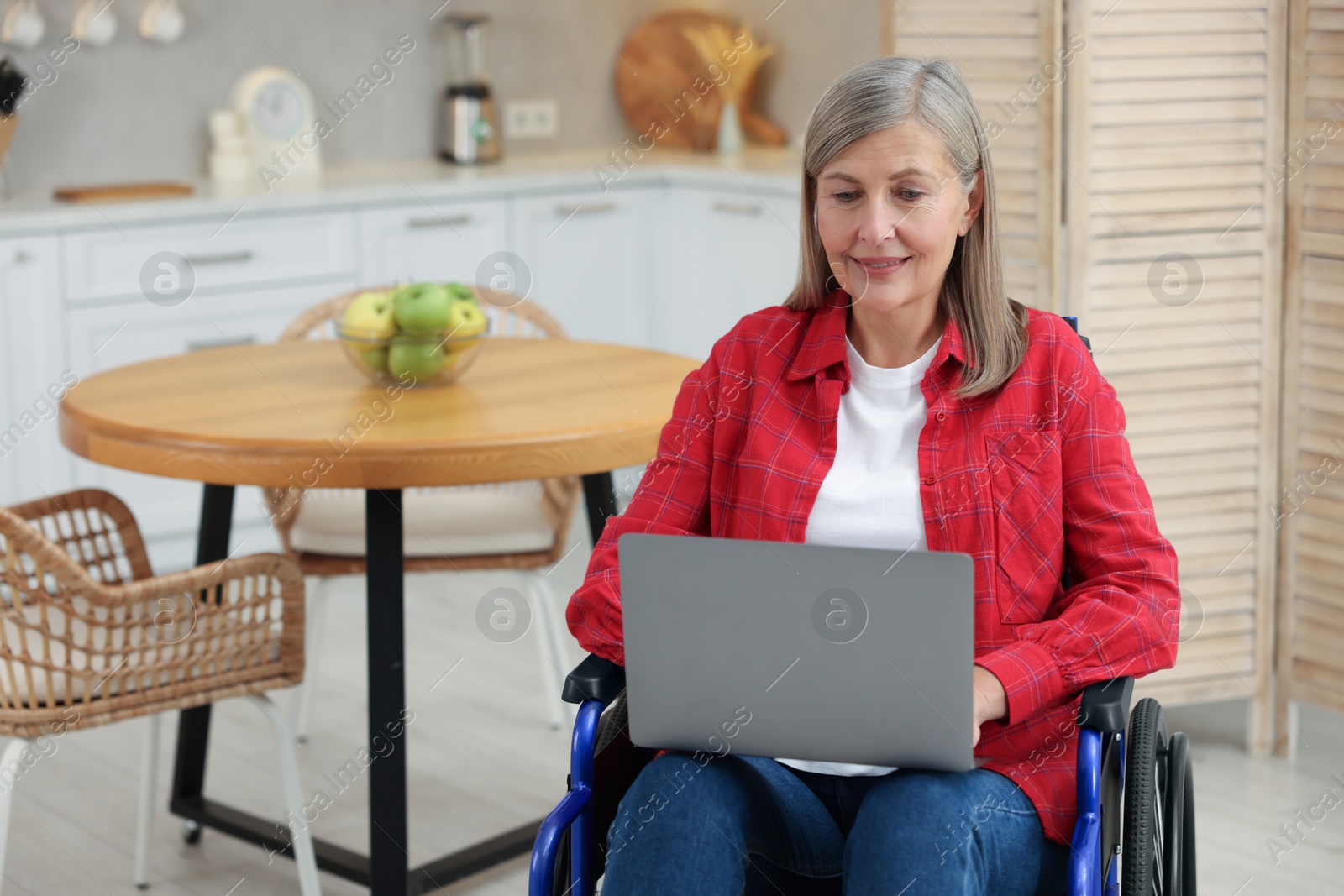 Photo of Woman in wheelchair using laptop at home