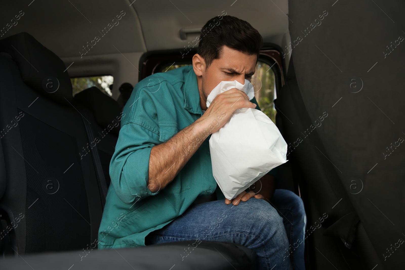 Photo of Man with paper bag suffering from nausea in car