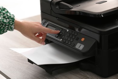Photo of Woman using modern printer in office, closeup