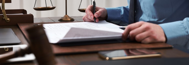 Lawyer working with documents at wooden table in office, closeup. Banner design