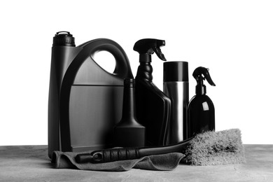 Bottles, brush and car wash cloth on grey table against white background