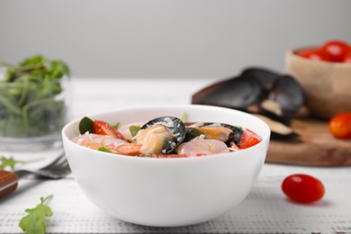 Photo of Bowl of delicious salad with seafood on white wooden table