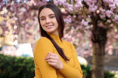 Beautiful woman near blossoming tree on spring day