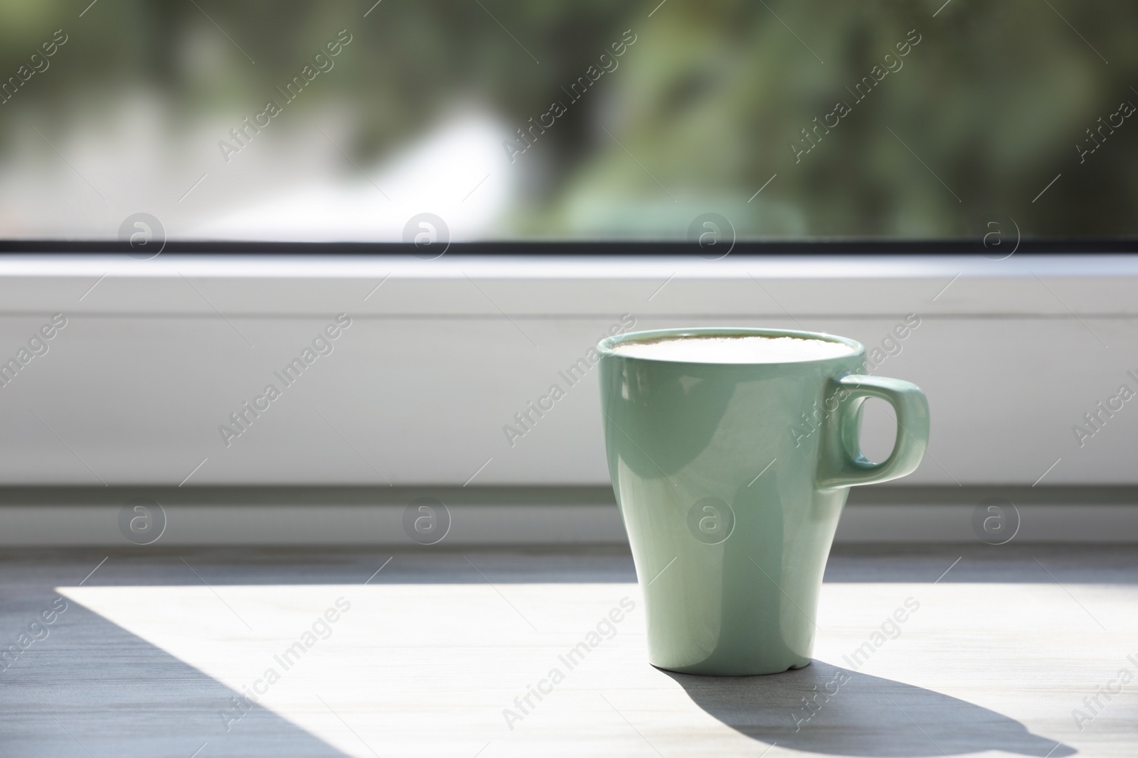 Photo of Cup of coffee on wooden window sill. Space for text