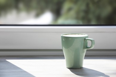 Cup of coffee on wooden window sill. Space for text