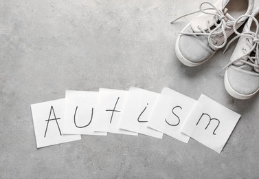 Notes with word "Autism" and child trainers on light background