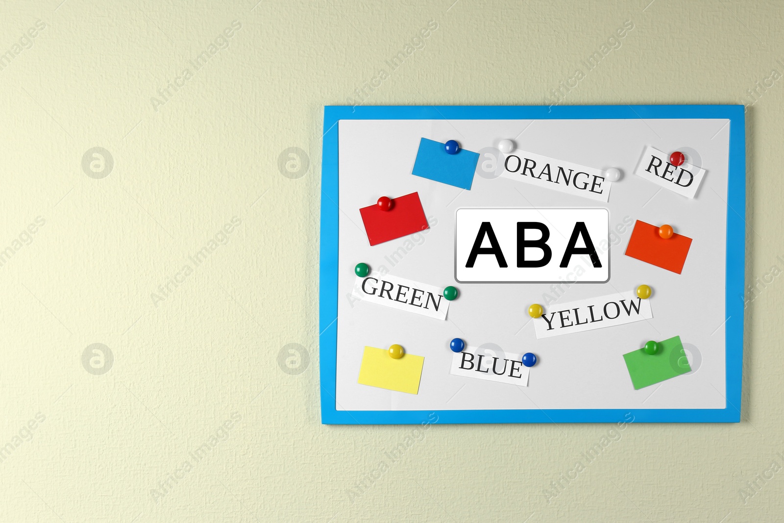 Photo of Board with abbreviation ABA and different colors on beige wall, space for text