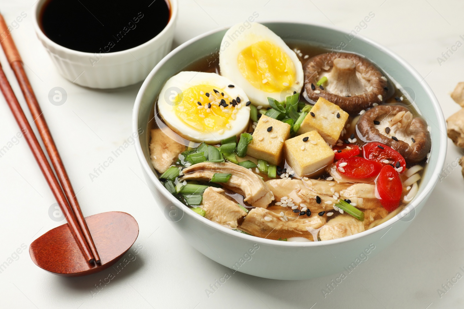 Photo of Delicious ramen served on white table, closeup. Noodle soup