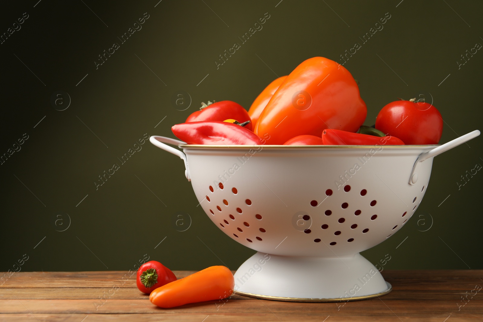 Photo of Colander with fresh vegetables on wooden table