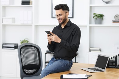 Happy young man using smartphone in office