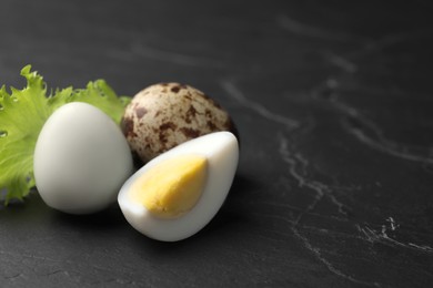 Photo of Unpeeled and peeled hard boiled quail eggs with lettuce leaf on black table, space for text