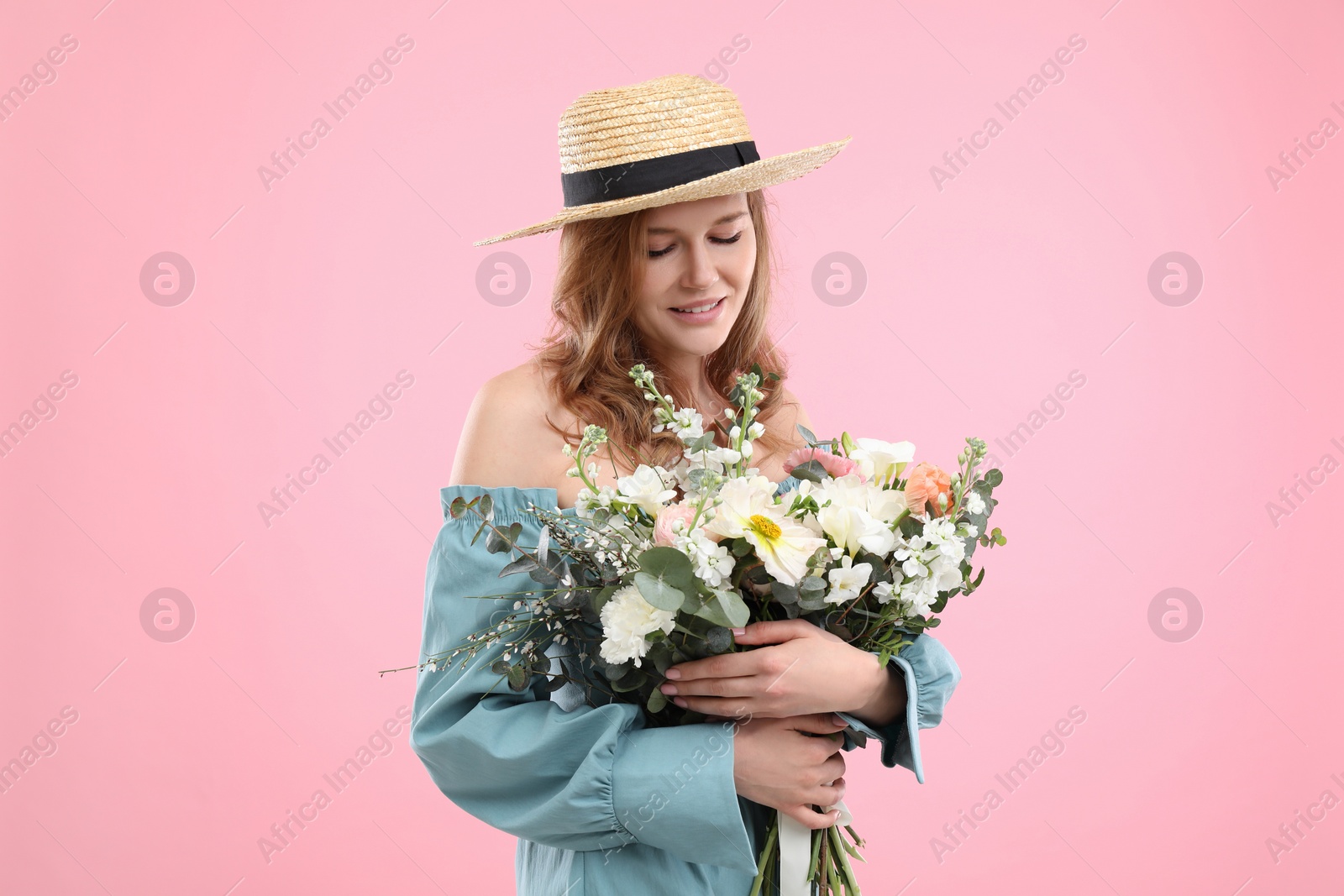 Photo of Beautiful woman in straw hat with bouquet of flowers on pink background