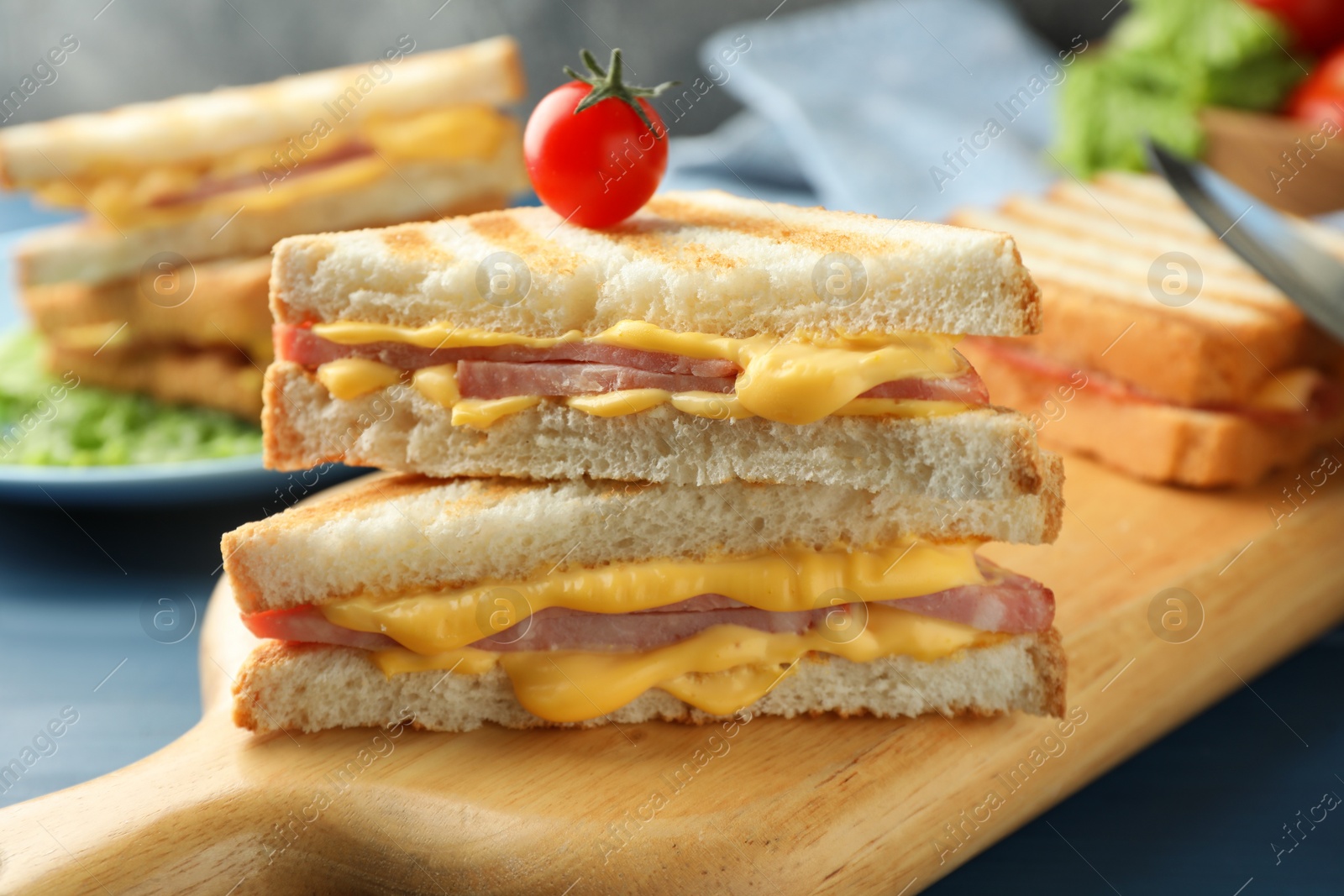 Photo of Tasty sandwiches with ham, melted cheese and tomato on table, closeup