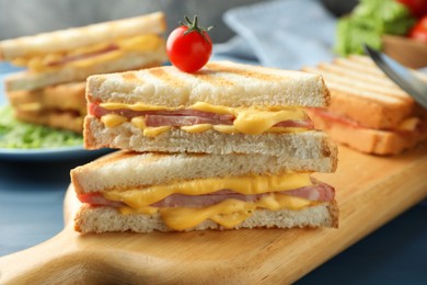 Tasty sandwiches with ham, melted cheese and tomato on table, closeup