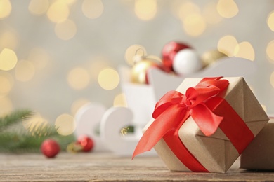 Photo of Gift box on table against blurred Christmas lights. Space for text