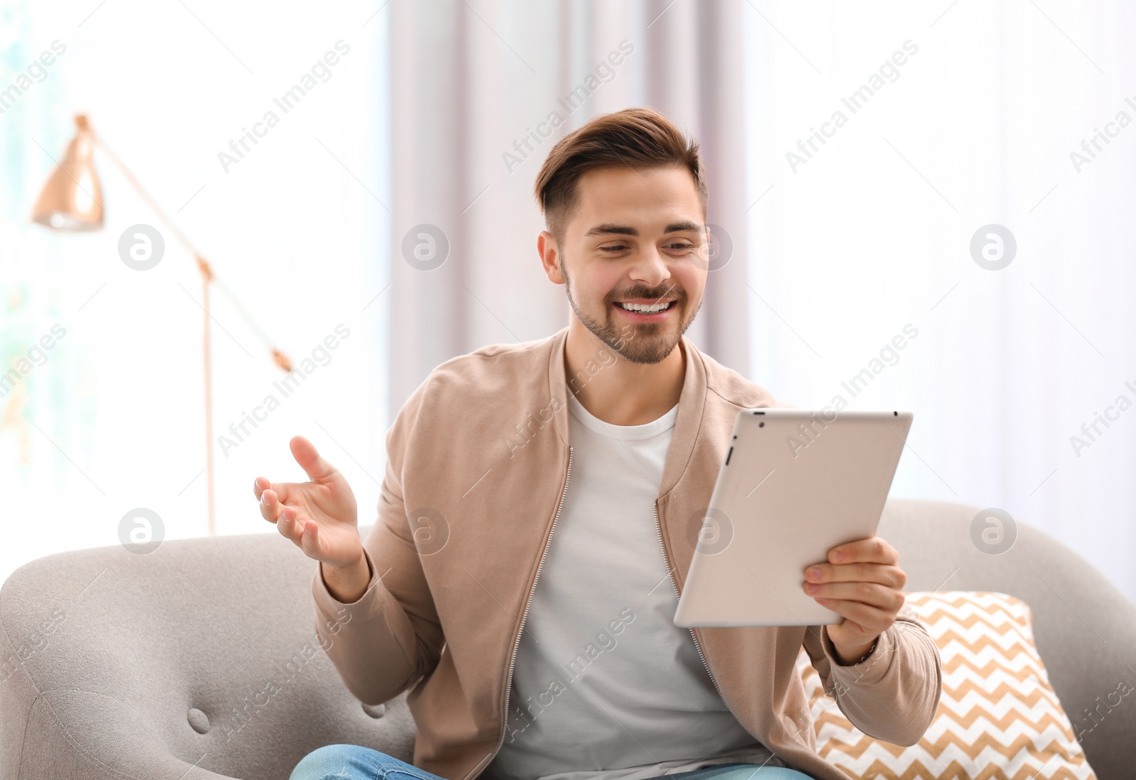 Photo of Man using tablet for video chat in living room