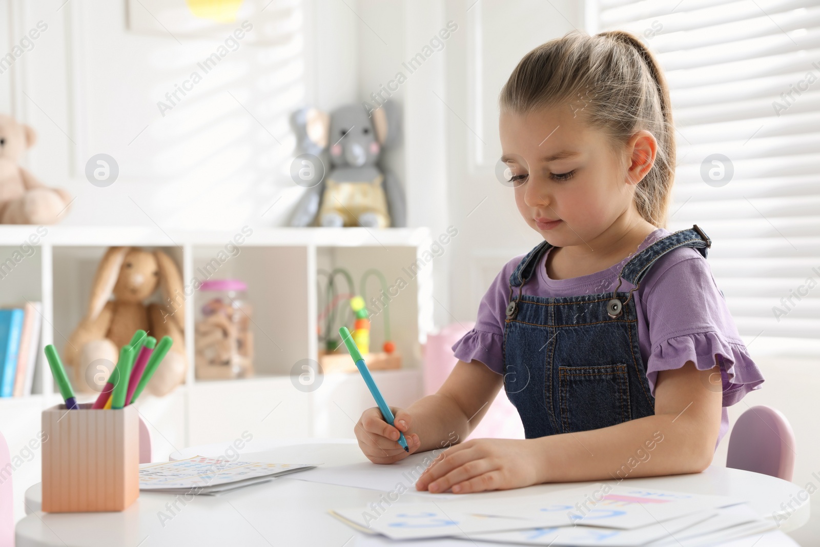 Photo of Little girl writing in classroom at English lesson