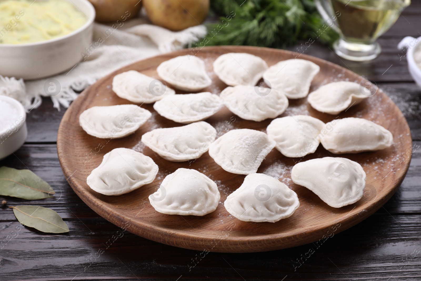 Photo of Raw dumplings (varenyky) and ingredients on brown wooden table