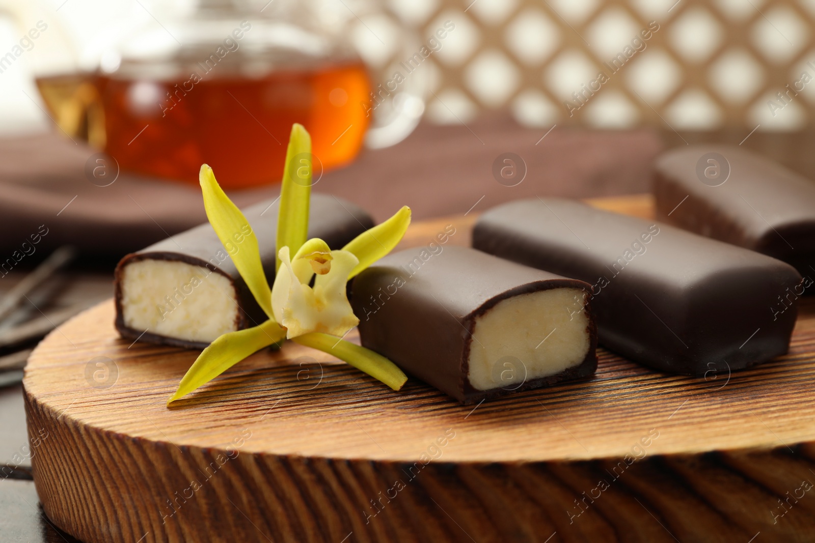 Photo of Glazed curd cheese bars and vanilla flower on wooden table, closeup