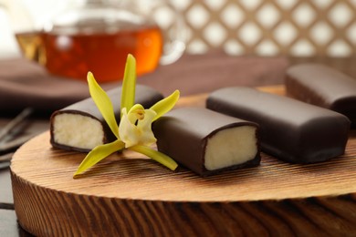 Photo of Glazed curd cheese bars and vanilla flower on wooden table, closeup