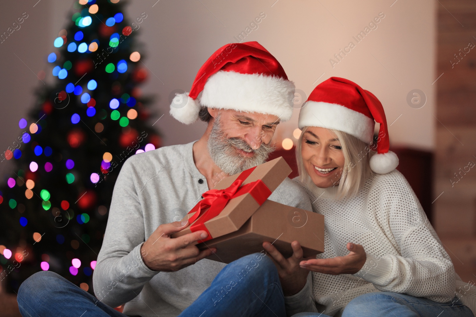 Photo of Happy couple opening Christmas gift at home