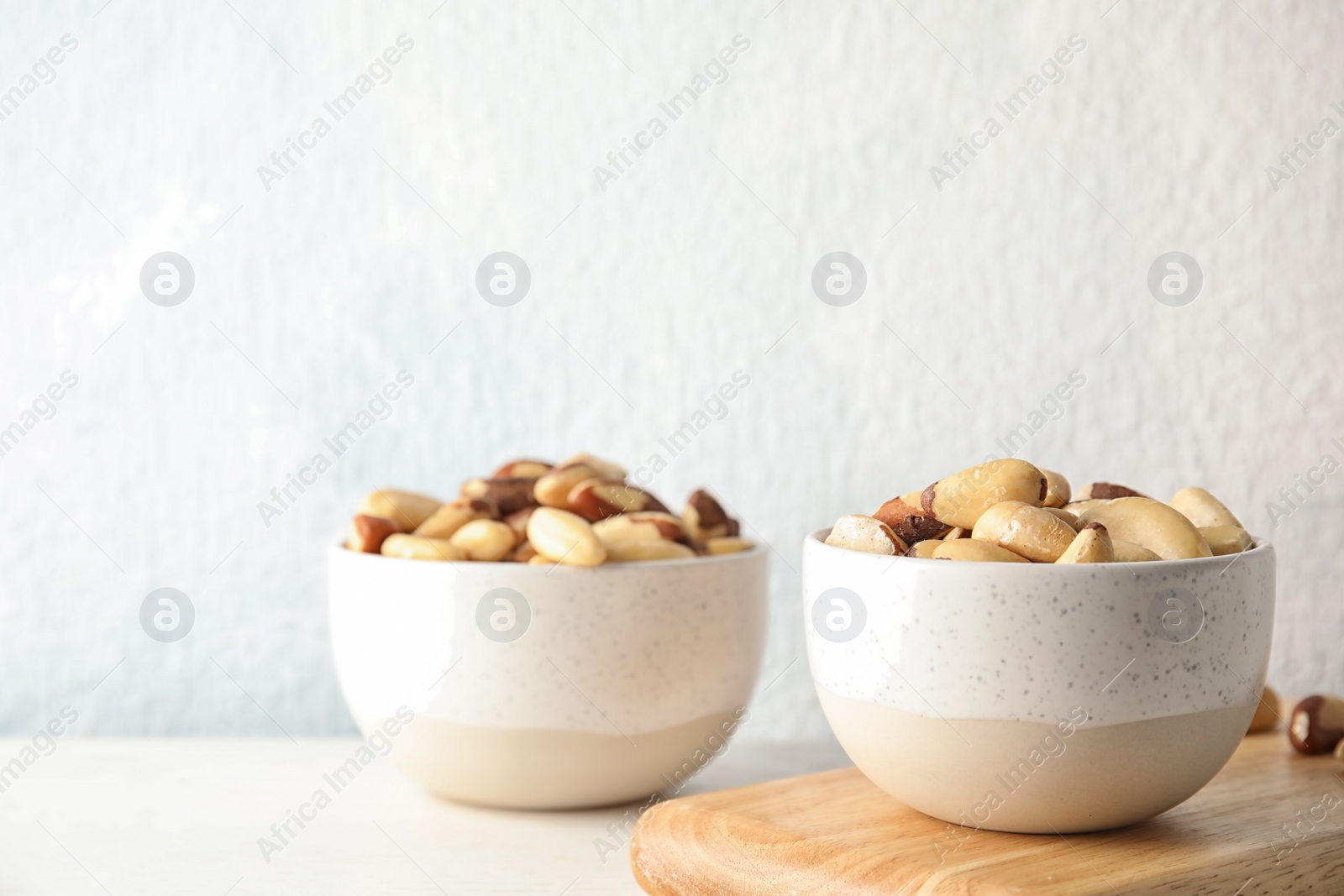 Photo of Bowls with tasty Brazil nuts on table. Space for text