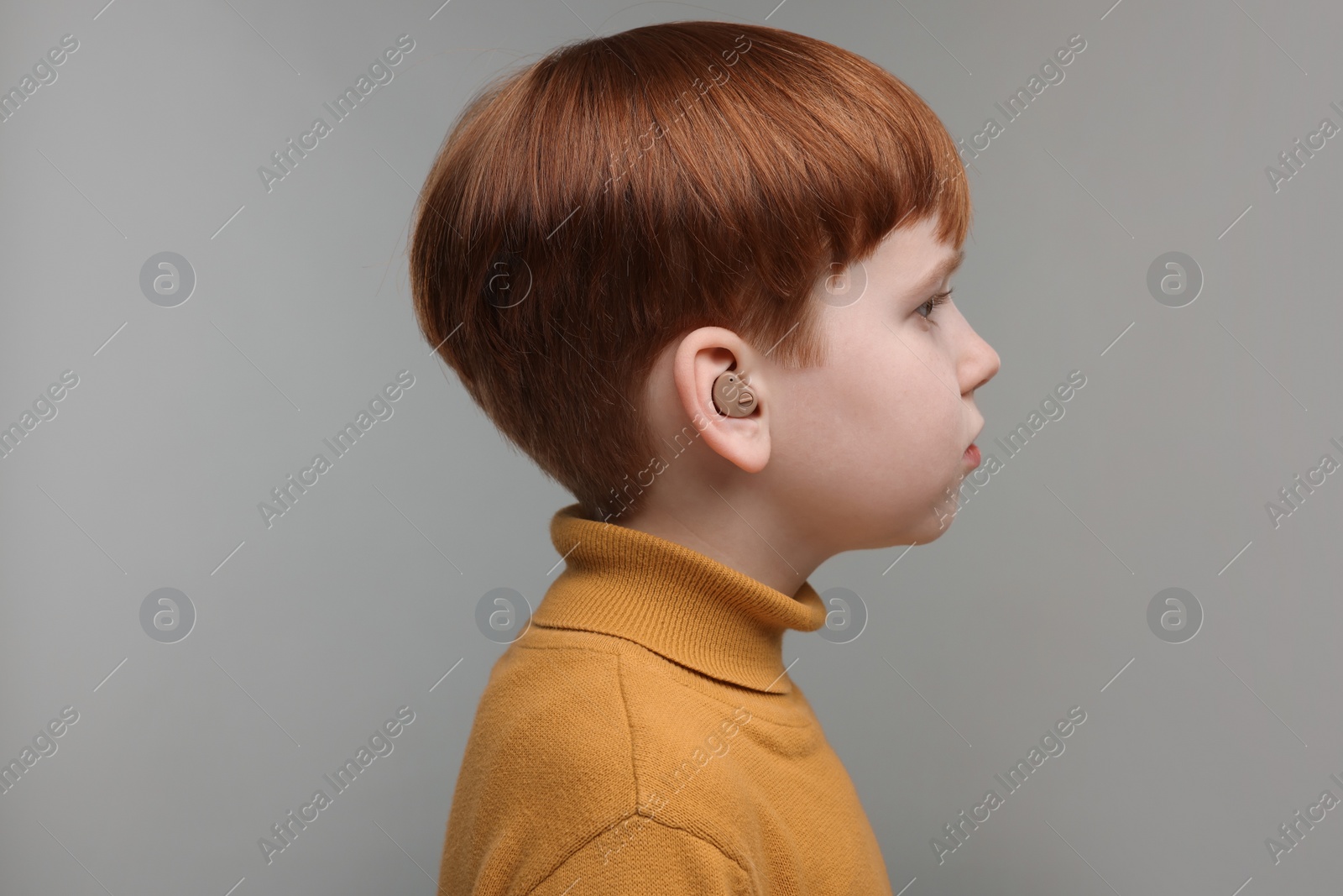 Photo of Little boy with hearing aid on grey background
