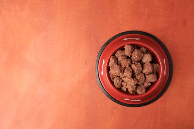 Wet pet food in feeding bowl on orange background, top view. Space for text