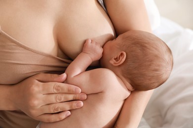 Photo of Mother breastfeeding her newborn baby at home, closeup