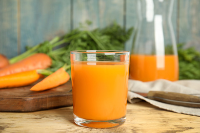 Photo of Glass of freshly made carrot juice on wooden table