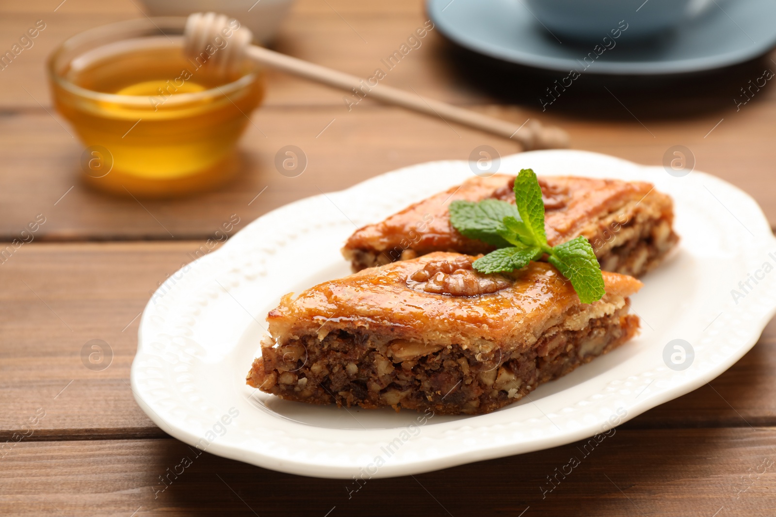 Photo of Delicious honey baklava with walnuts on wooden table, closeup