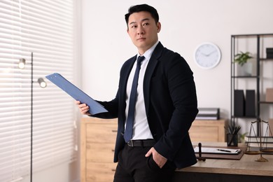 Portrait of confident notary with clipboard in office