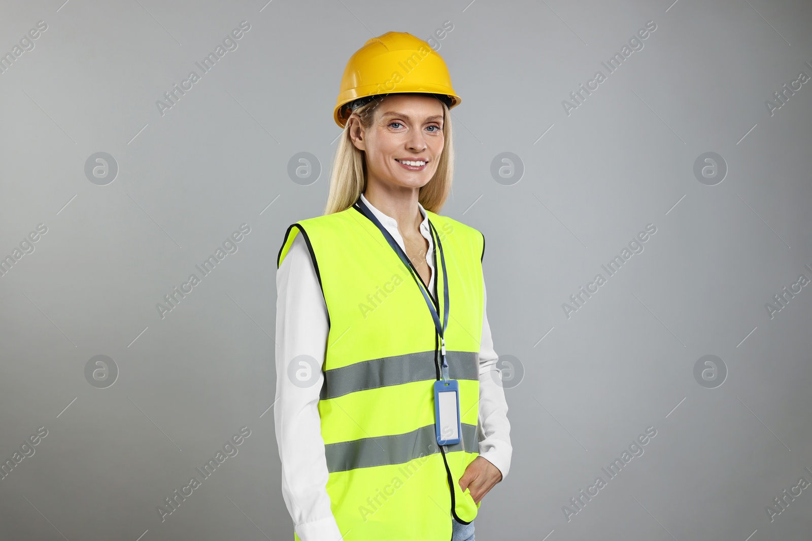 Photo of Engineer with hard hat and badge on grey background