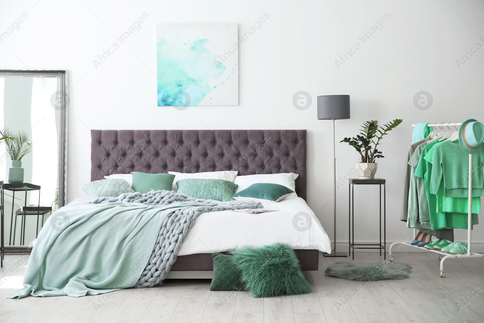 Photo of Stylish bedroom interior with clothes rack and mint decor elements