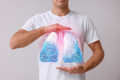 Image of Man holding hands near chest with illustration of lungs on grey background, closeup