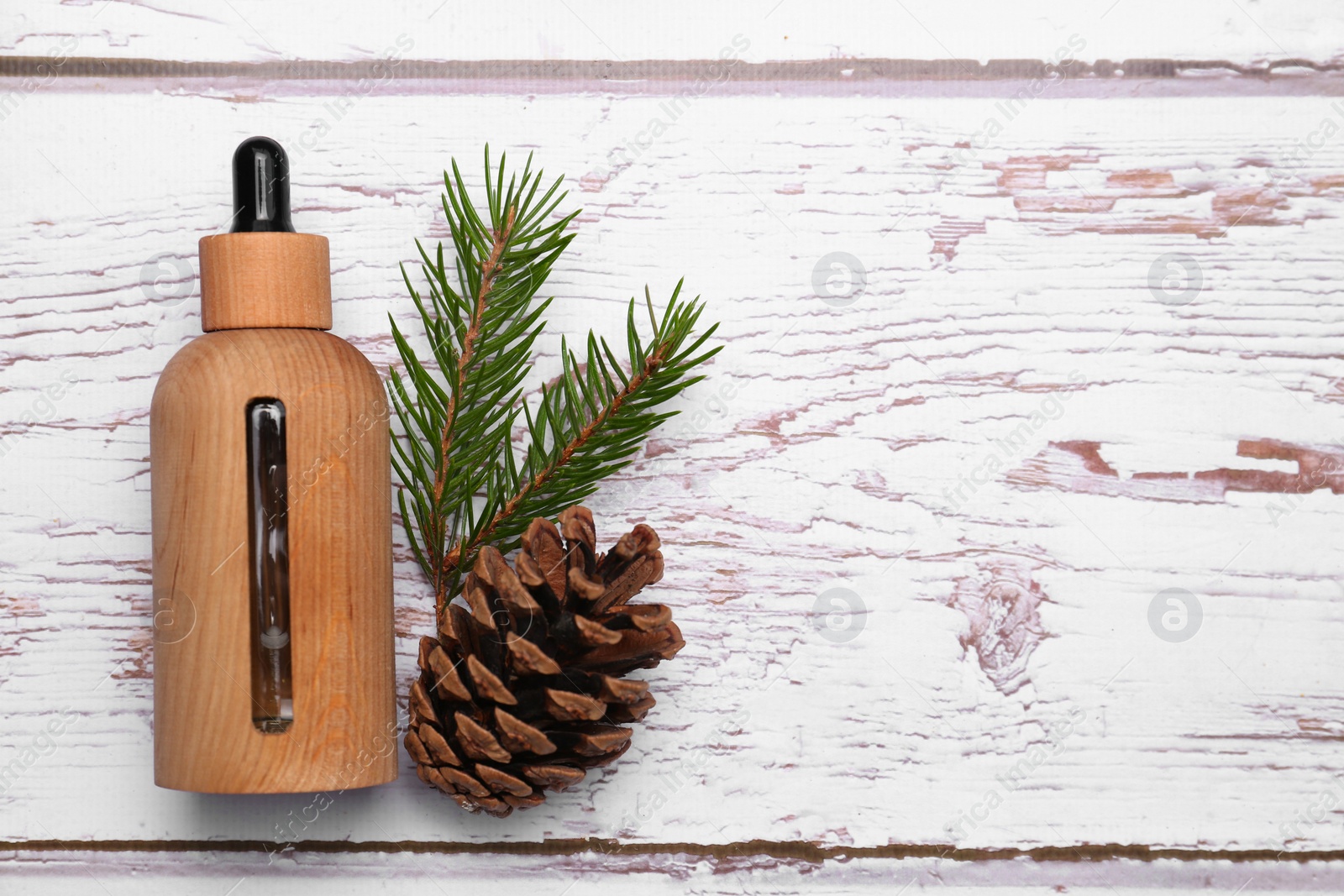Photo of Bottle of pine essential oil, conifer tree branch and cone on white wooden table, top view. Space for text
